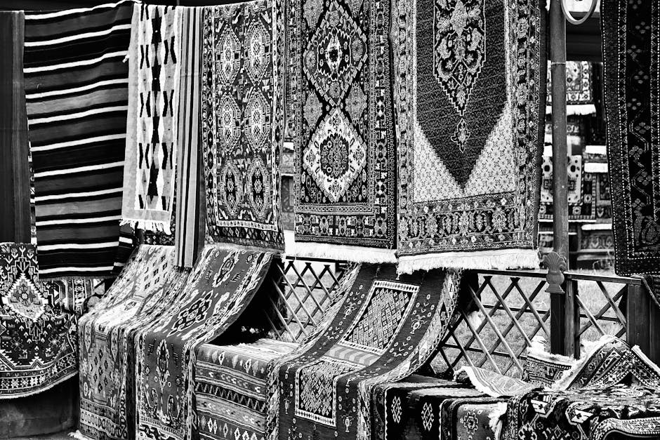A row of tightly rolled vintage Persian rugs with intricate floral and geometric patterns in vibrant colors such as red, blue, yellow, and beige, displayed vertically on a shop shelf under bright ligh